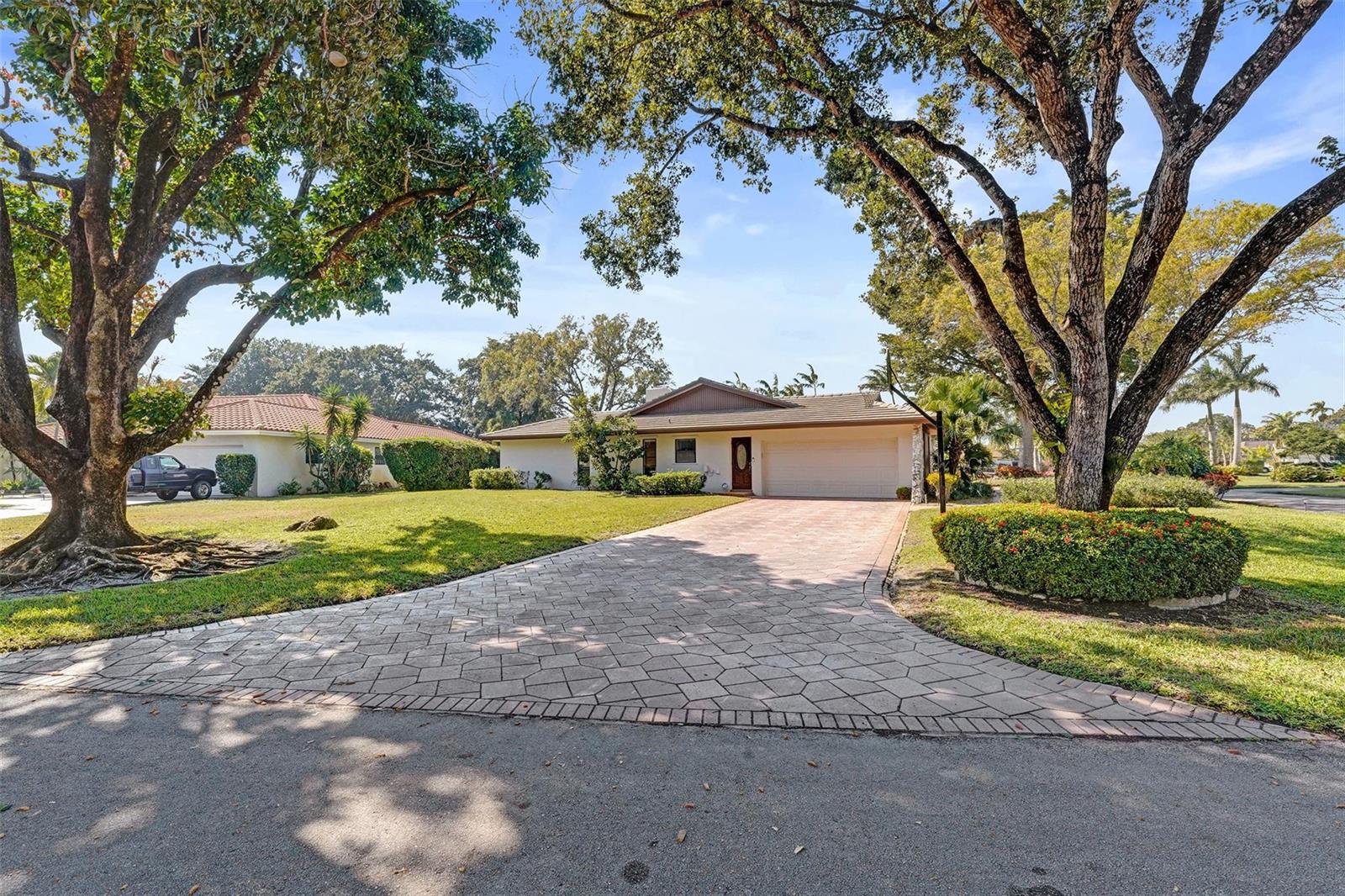 A single-story house with a paved driveway and large trees in the front yard — 9600 Conch Shell Manor, Plantation FL 33324, PLANTATION, FL