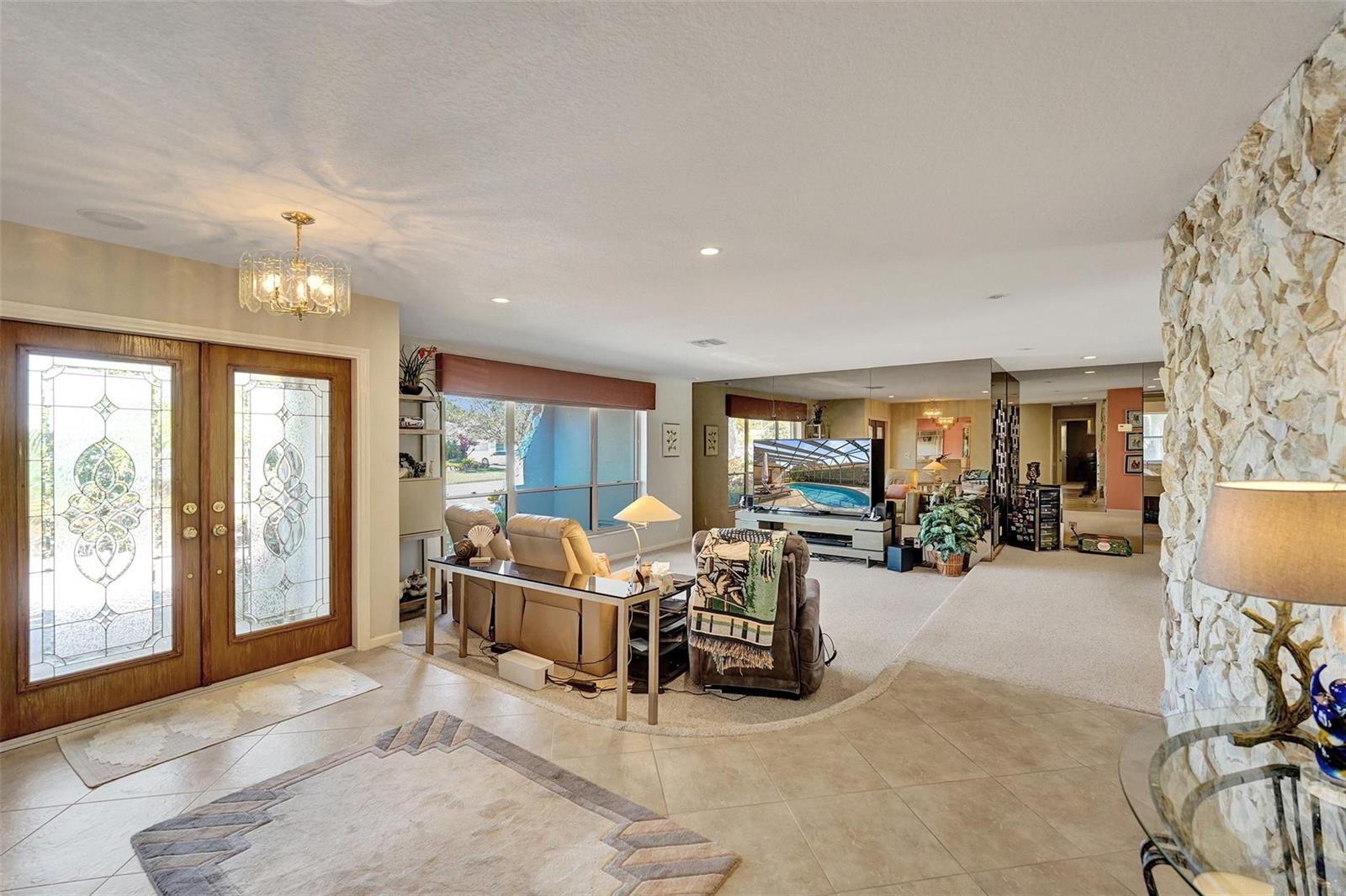 A living room features a stone accent wall, tiled entryway, carpeted seating area, and glass doors — 9600 Conch Shell Manor, Plantation FL 33324, PLANTATION, FL