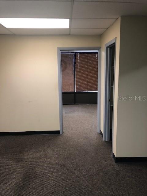 An interior view shows a carpeted office space with a doorway leading to another room — 7211 N DALE MABRY HIGHWAY N, TAMPA, FL