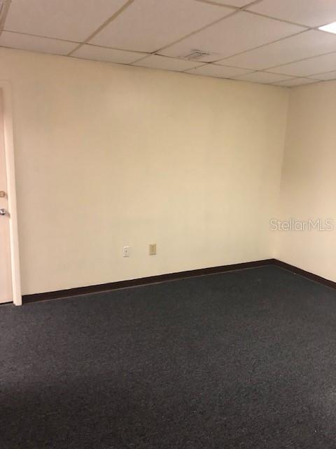 An empty room features beige walls, dark gray carpeting, and a drop ceiling — 7211 N DALE MABRY HIGHWAY N, TAMPA, FL