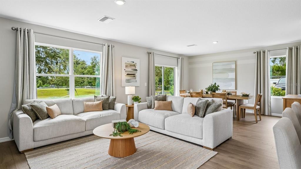 A living room and dining area with light-colored sofas, a round coffee table, and windows — 17972 ACORN DROP ROAD, LAND O LAKES, FL