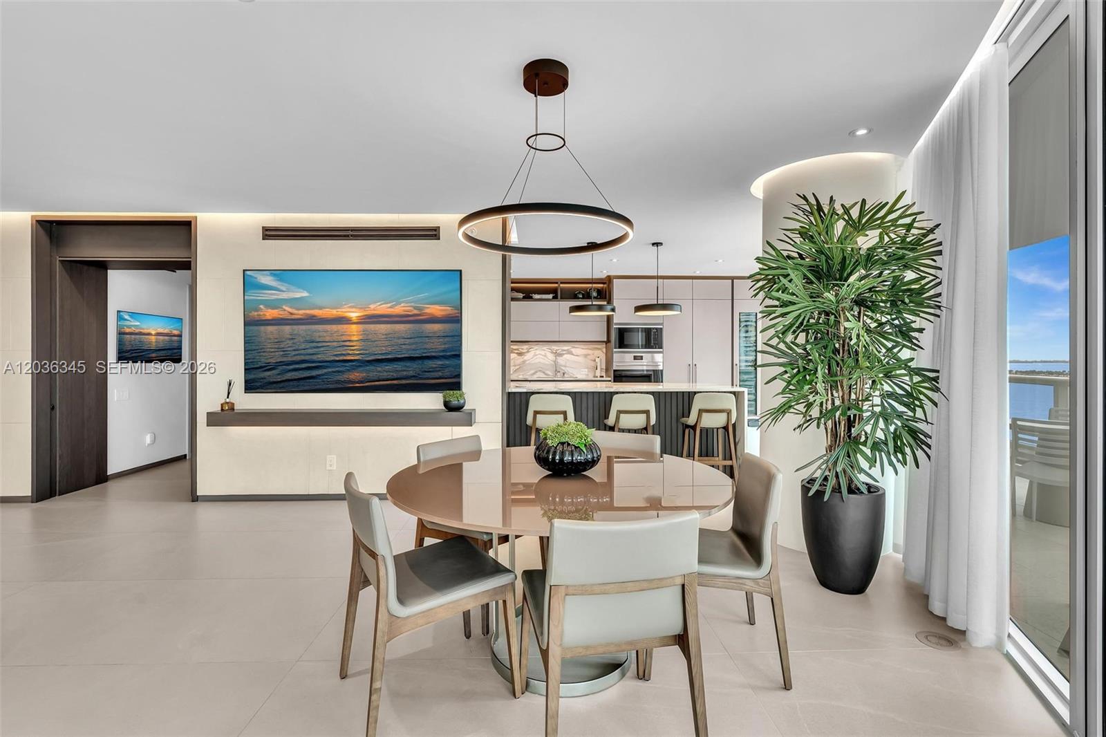 A modern dining area features a round table, contemporary chairs, and an open-concept kitchen — 2127 Brickell Ave # 1002, Miami FL 33129, MIAMI, FL
