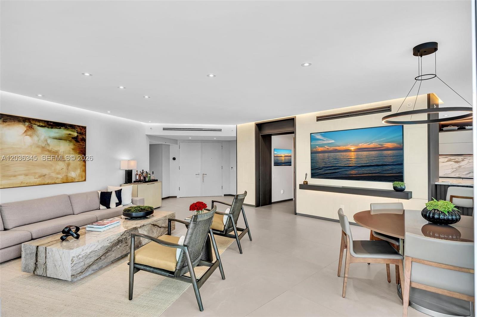 A modern living and dining area features a stone coffee table, sofa, and wall-mounted television — 2127 Brickell Ave # 1002, Miami FL 33129, MIAMI, FL