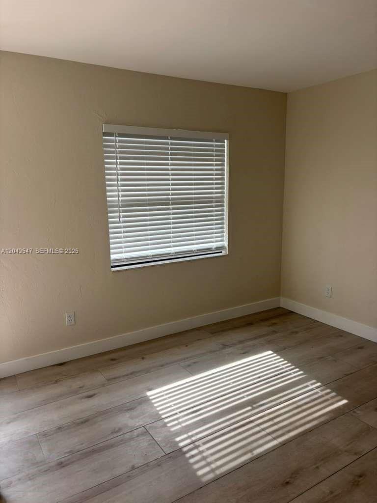 An empty room features light-colored wood-look flooring, beige walls, and a window with blinds — 418 Las Palmas Cir # 0, Avon Park FL 33825, AVON PARK, FL