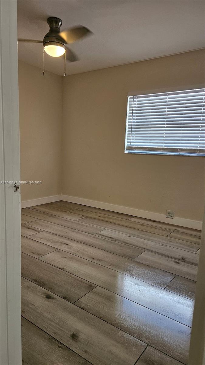 An empty bedroom features light-colored wood-look tile flooring, beige walls, and a ceiling fan — 418 Las Palmas Cir # 0, Avon Park FL 33825, AVON PARK, FL
