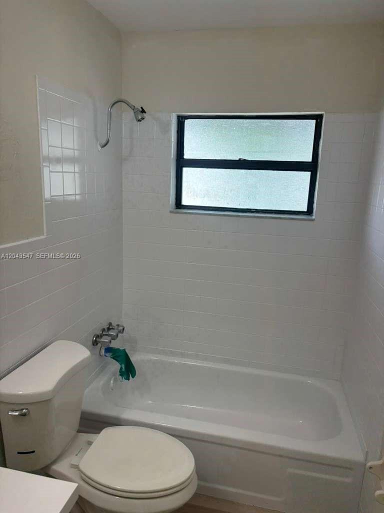 A bathroom features a white toilet, a bathtub with a showerhead, and white tiled walls — 418 Las Palmas Cir # 0, Avon Park FL 33825, AVON PARK, FL