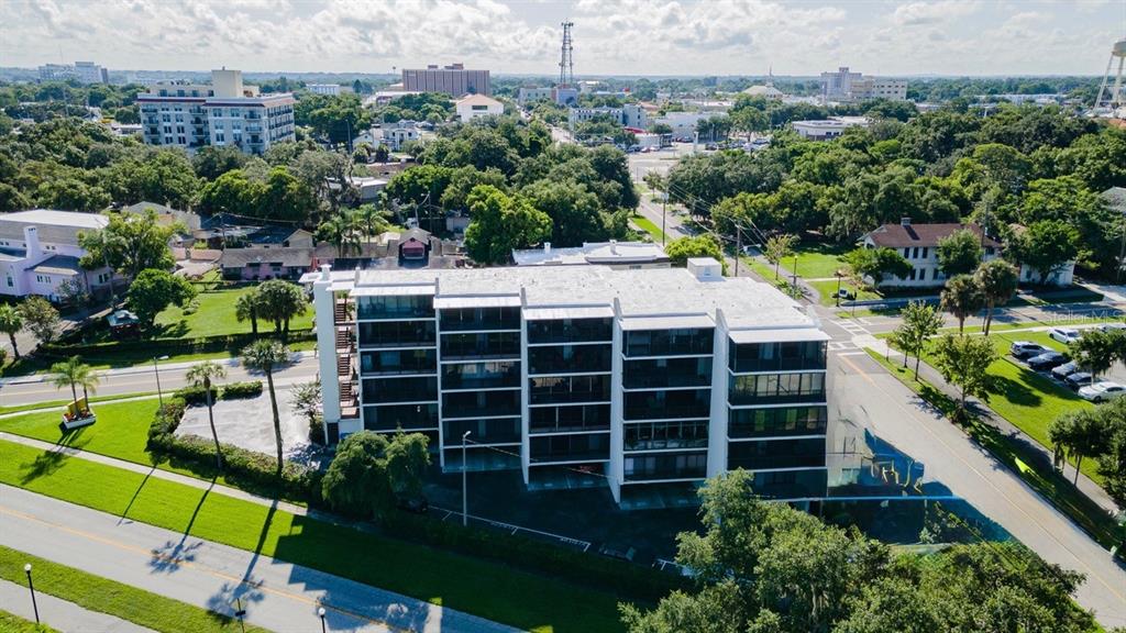 An aerial view of a multi-story apartment building surrounded by trees and paved roads — 208 LAKE HOWARD DRIVE NW UNIT 104, WINTER HAVEN, FL