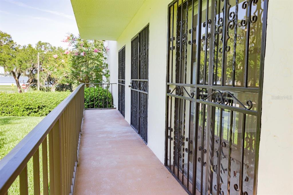 A covered balcony features a concrete floor, metal railings, and decorative security doors — 208 LAKE HOWARD DRIVE NW UNIT 104, WINTER HAVEN, FL