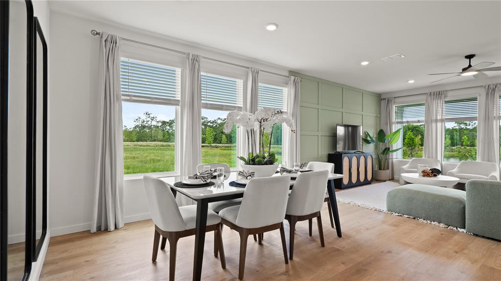 A dining and living area features light wood floors, a green accent wall, and windows — 4883 WALTHAM FOREST DRIVE, DAVENPORT, FL