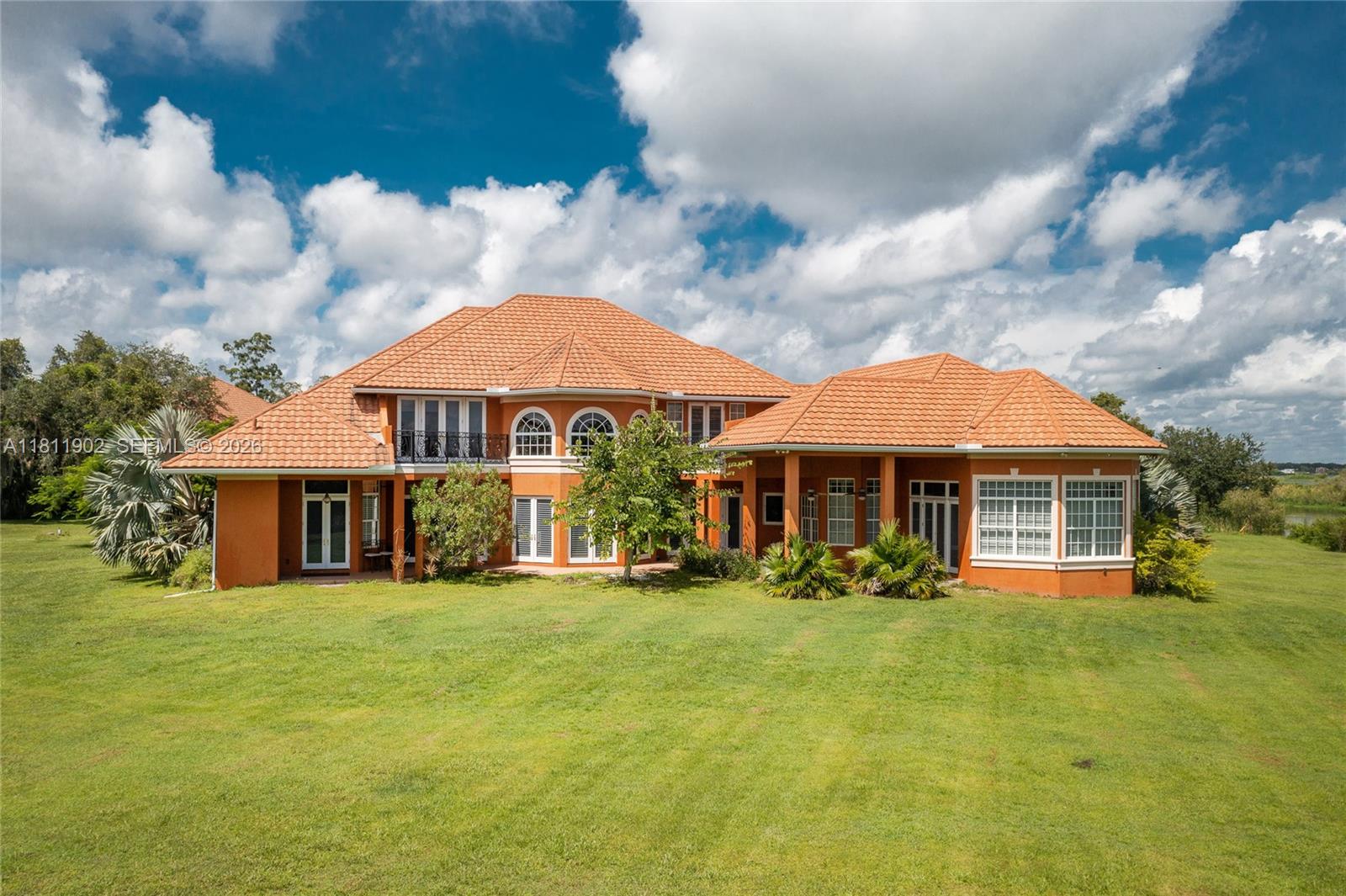 A large orange house with a tiled roof sits on a wide grassy lawn — 37511 Washington Loop Road, Punta Gorda FL 33982, PUNTA GORDA, FL