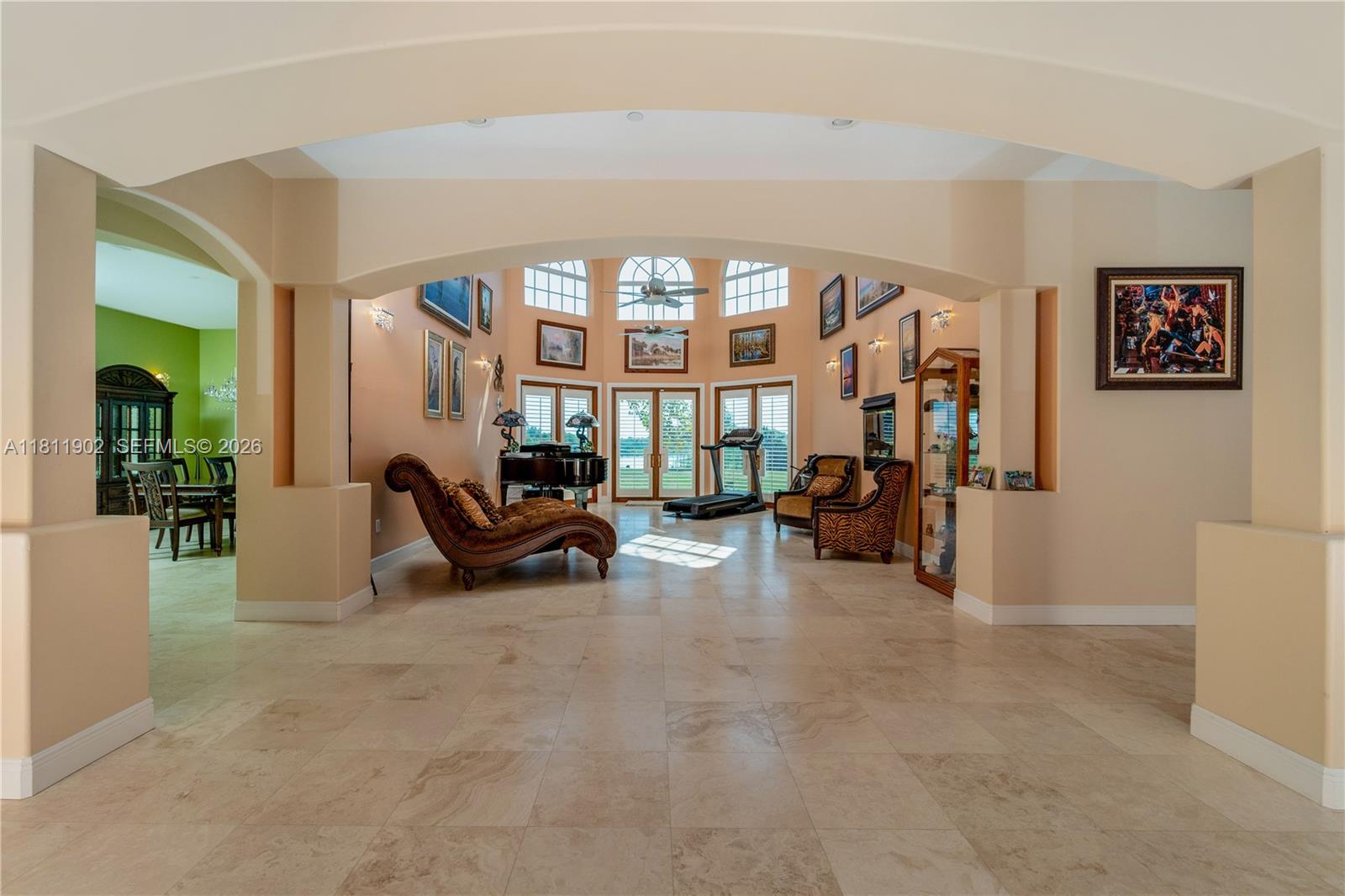 A spacious living area features tile flooring, arched entryways, a grand piano, and large windows — 37511 Washington Loop Road, Punta Gorda FL 33982, PUNTA GORDA, FL