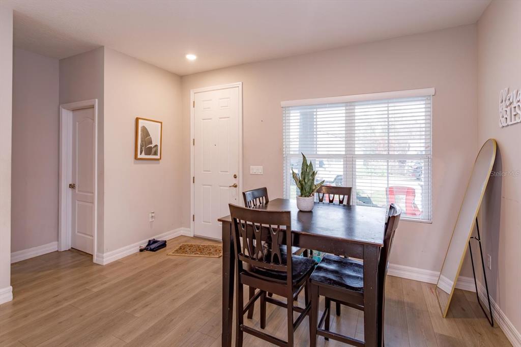 A dining area features light wood flooring, a dark table with chairs, and a window — 884 KLONDIKE STREET, WINTER GARDEN, FL
