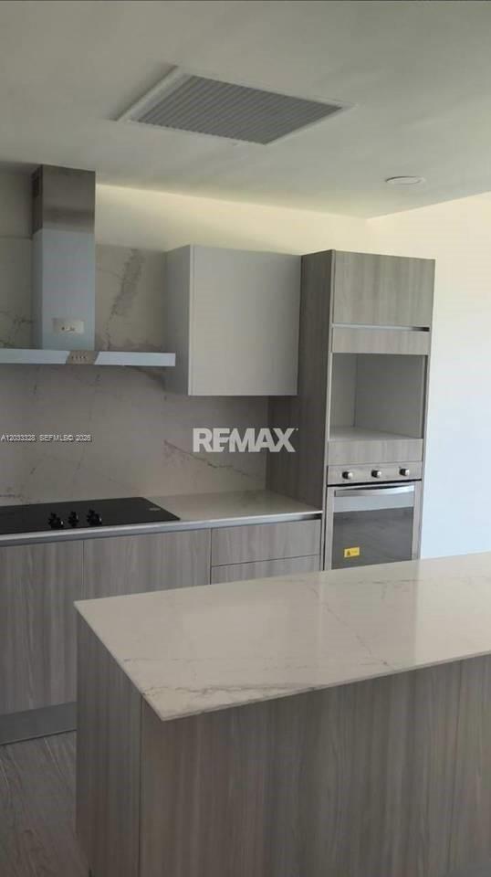 A modern kitchen features light wood cabinetry, a white marble island, and a stainless steel oven — 1 Cap Cana # 1, FL, FL