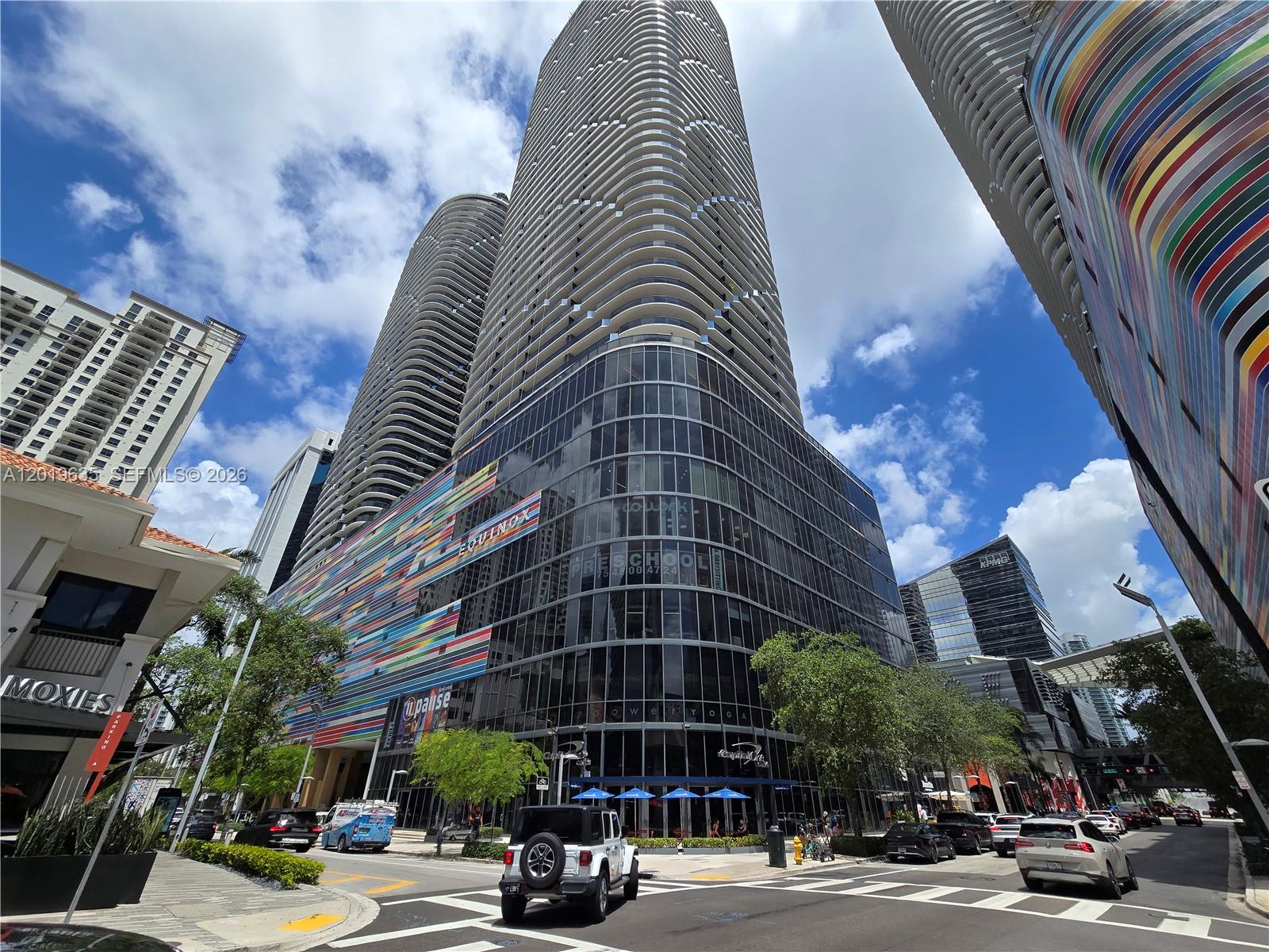 A low-angle view of a modern high-rise building with a colorful, striped facade — 55 SW 9th St # 1810, Miami FL 33130, MIAMI, FL