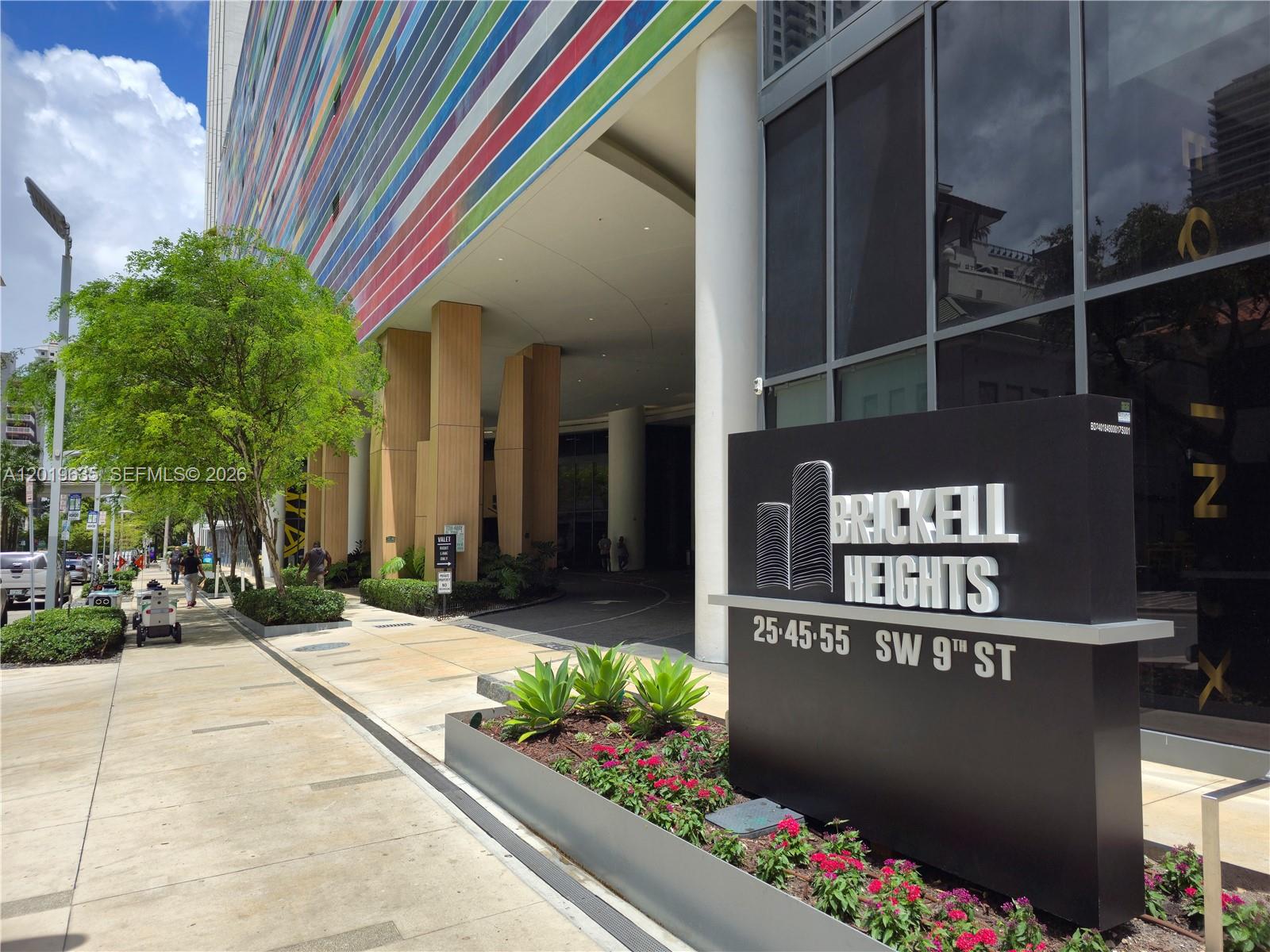 A sign for Brickell Heights stands in front of a building with a colorful facade — 55 SW 9th St # 1810, Miami FL 33130, MIAMI, FL