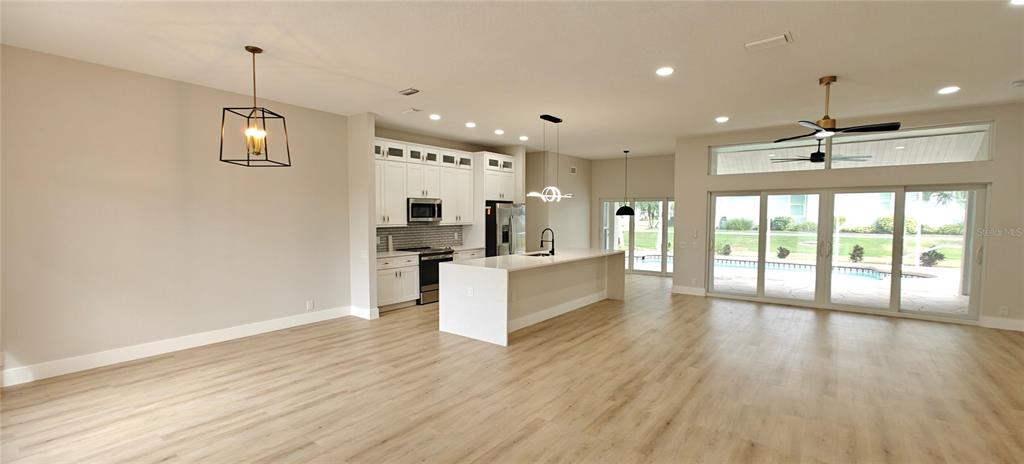 An open-concept kitchen and living area features white cabinetry, a central island, and sliding doors — 2531 PEBBLE CREEK PLACE, PORT CHARLOTTE, FL