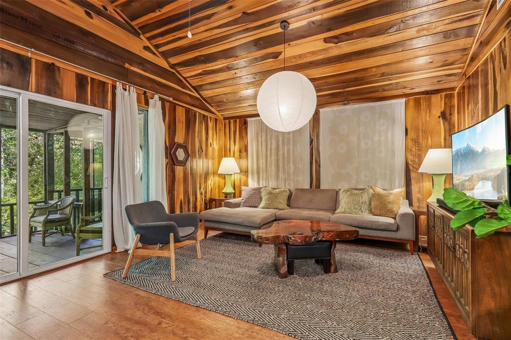A living room features wood-paneled walls and ceiling, a sectional sofa, and a large pendant light — 18930 NE 143RD AVENUE, FORT MC COY, FL