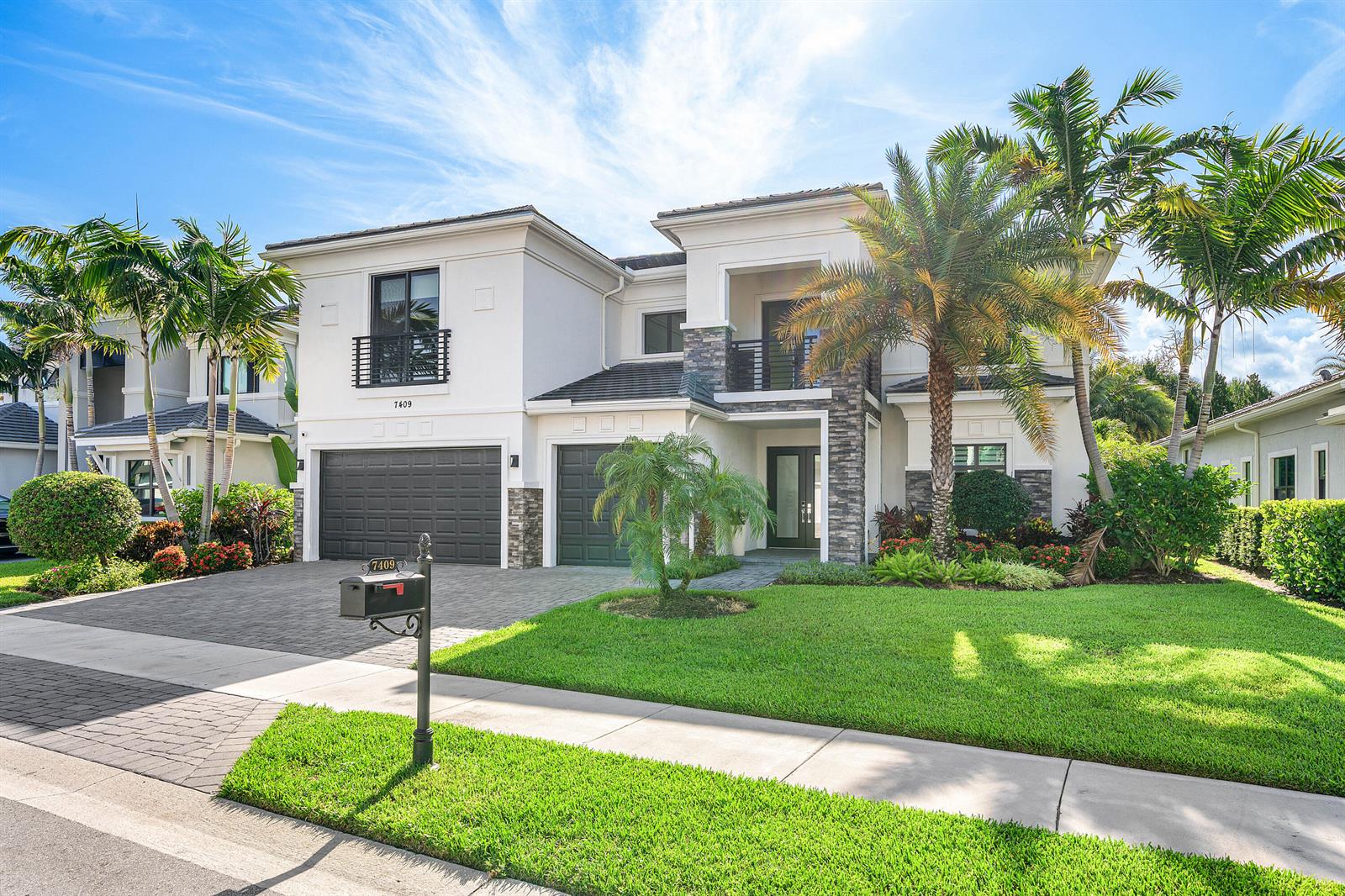 A two-story house with a paved driveway, palm trees, and a stone-accented facade — 7409 NW 25th Terrace, Boca Raton FL 33496, BOCA RATON, FL