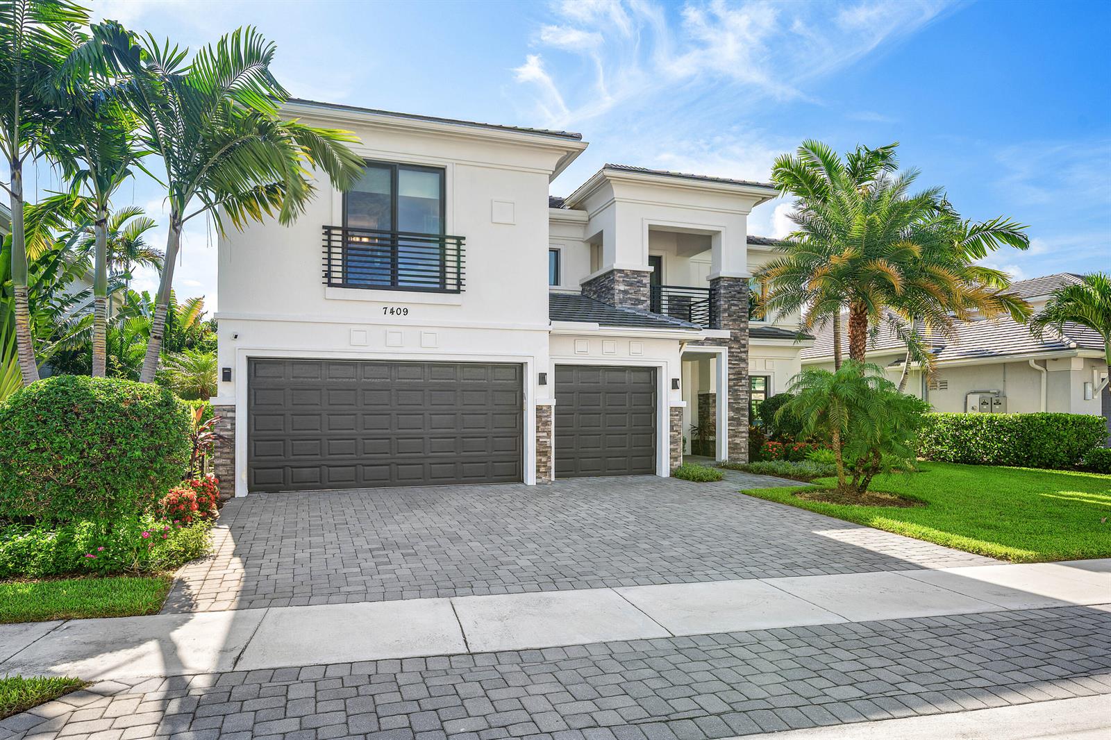 A two-story house features a paved driveway, two garage doors, and palm trees — 7409 NW 25th Terrace, Boca Raton FL 33496, BOCA RATON, FL
