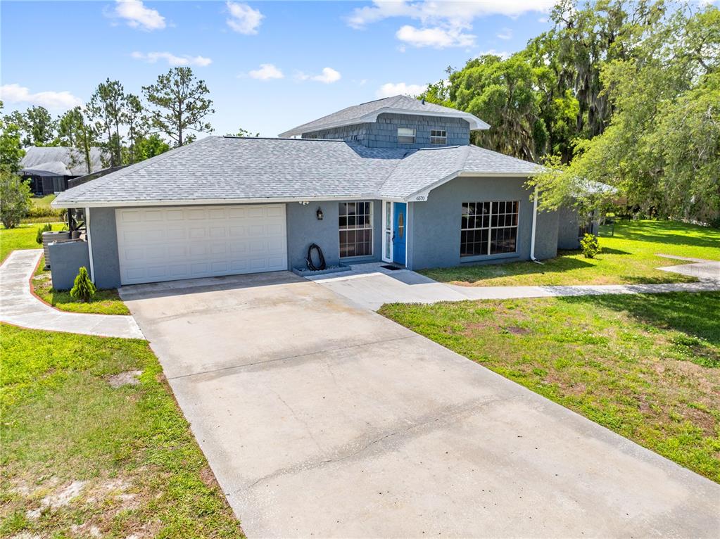 A gray house with a two-car garage, blue front door, and a second-story dormer — 6570 BAY SHORE DRIVE, ST CLOUD, FL