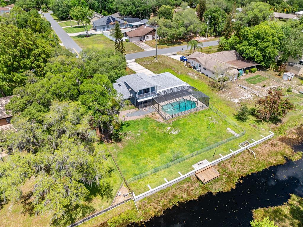 An aerial view of a house with a pool enclosure and a backyard canal — 6570 BAY SHORE DRIVE, ST CLOUD, FL