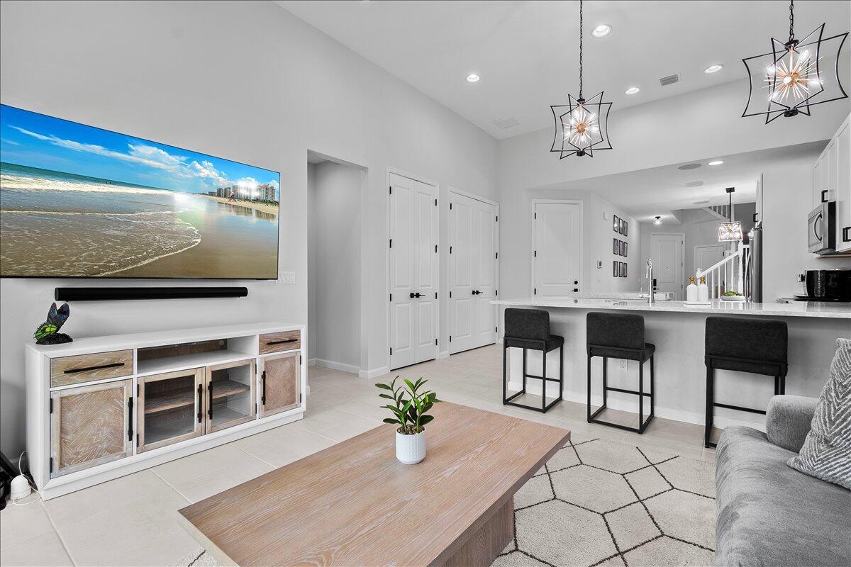 A modern living room features a large television, a wooden coffee table, and kitchen seating — 16493 Helix Court, Westlake FL 33470, WESTLAKE, FL