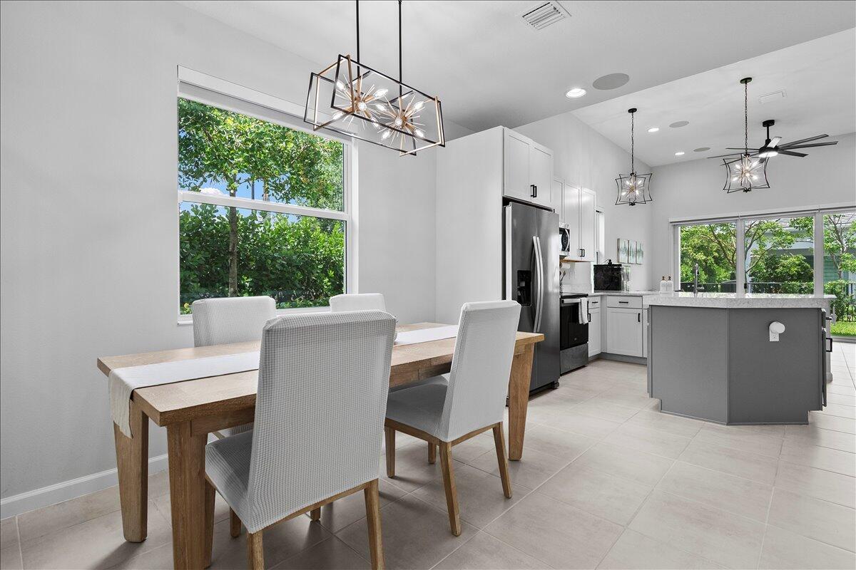 A dining area with a wooden table and chairs sits adjacent to a modern kitchen — 16493 Helix Court, Westlake FL 33470, WESTLAKE, FL