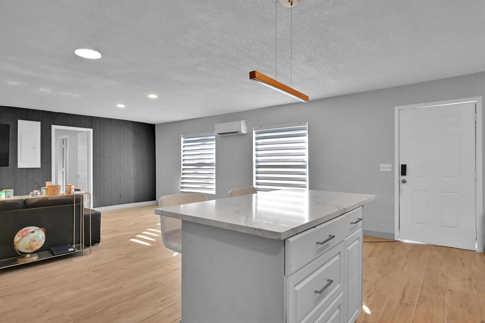 A kitchen island with a marble countertop sits in a room with light wood flooring — 6385 86th Place, Vero Beach FL 32958, VERO BEACH, FL