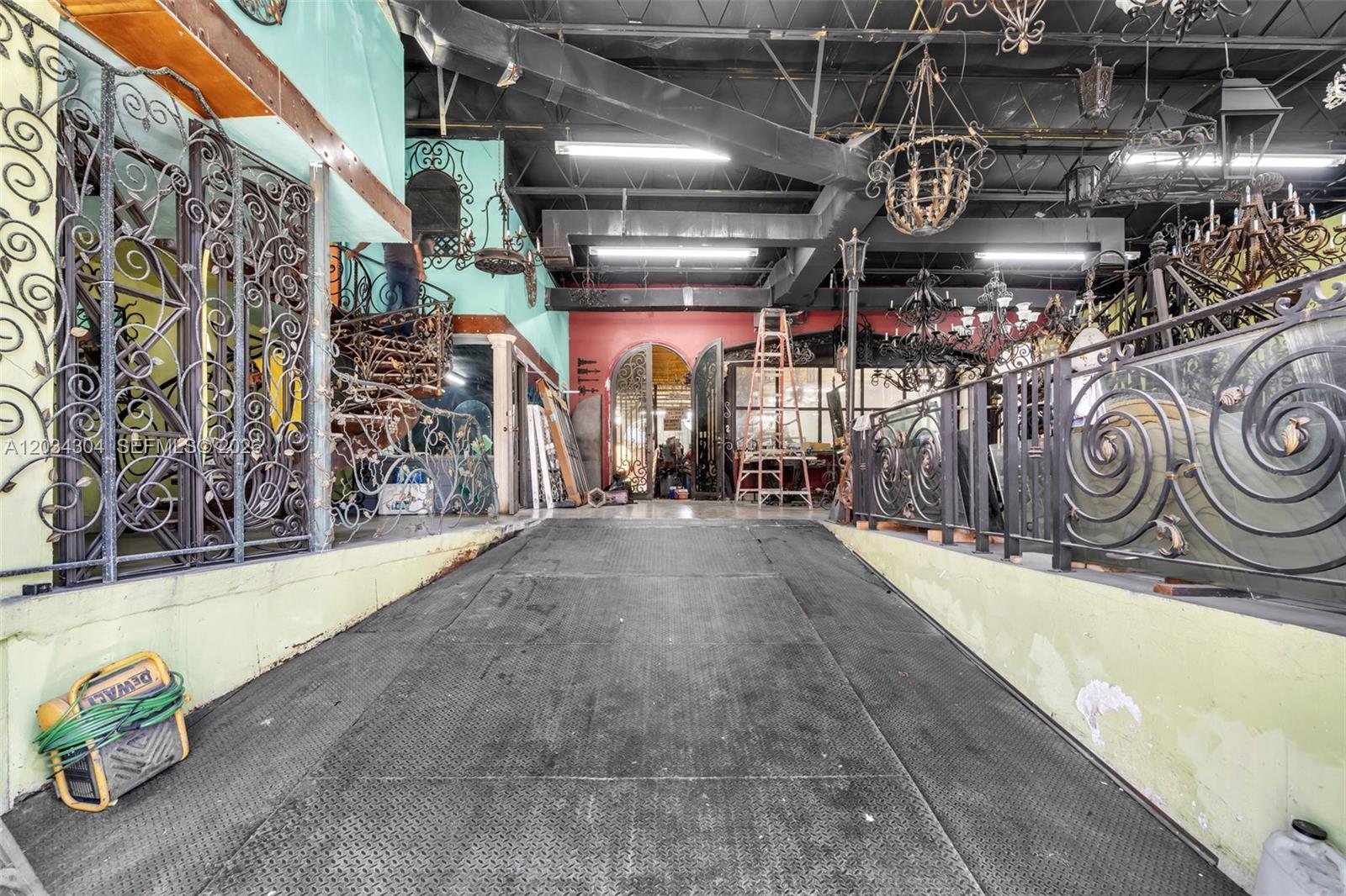 An industrial-style showroom features metal railings, hanging chandeliers, and a central ramped walkway — 341 W 21st St, Hialeah FL 33010, HIALEAH, FL