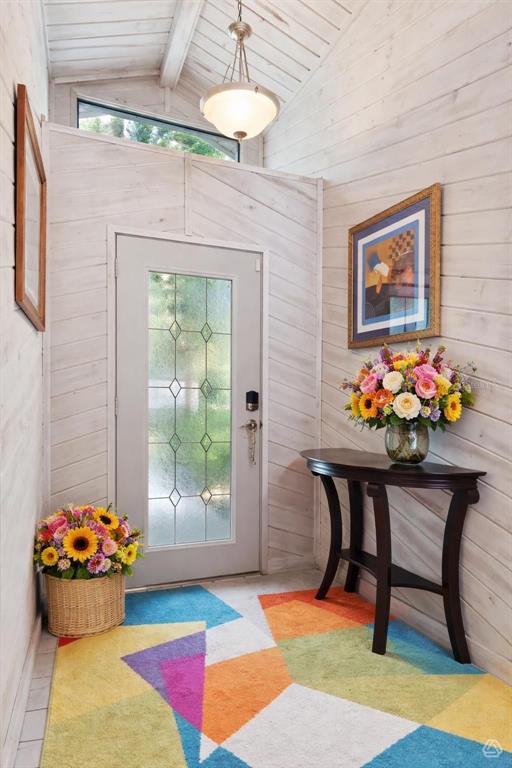 An entryway features white wood-paneled walls, a glass-paneled door, a colorful rug, and floral arrangements — 2610 TWELVE POINT DRIVE, LAKELAND, FL