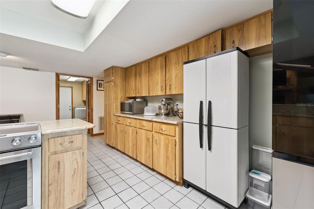 A kitchen features light wood cabinets, white tile flooring, and a white double-door refrigerator — 2610 TWELVE POINT DRIVE, LAKELAND, FL