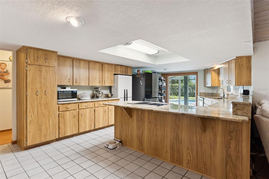 A kitchen with wood cabinets, granite countertops, tile flooring, and a large central island — 2610 TWELVE POINT DRIVE, LAKELAND, FL
