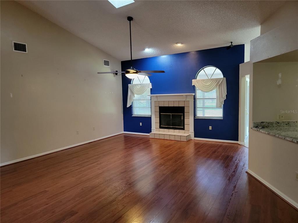 A living room features hardwood floors, a vaulted ceiling, and a fireplace on a blue wall — 1602 YEOMANS PATH, LAKELAND, FL