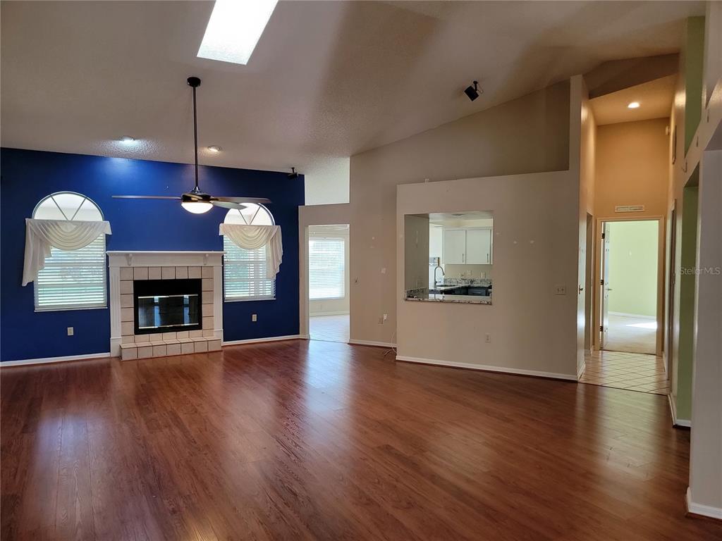 A living room with wood floors, a blue accent wall, and a fireplace — 1602 YEOMANS PATH, LAKELAND, FL
