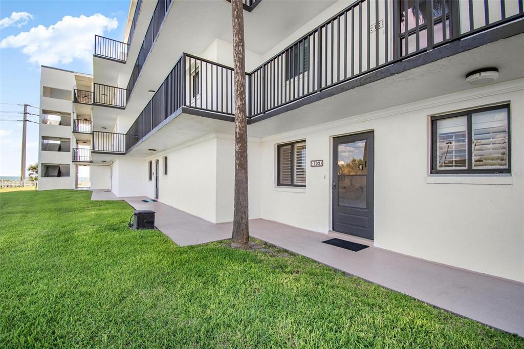 The exterior of a multi-story apartment building features a ground-floor unit with a private entrance — 3500 S OCEAN SHORE BOULEVARD UNIT 109, FLAGLER BEACH, FL