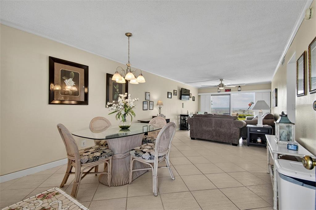 A dining area with a glass table and wicker chairs opens into a living room — 3500 S OCEAN SHORE BOULEVARD UNIT 109, FLAGLER BEACH, FL
