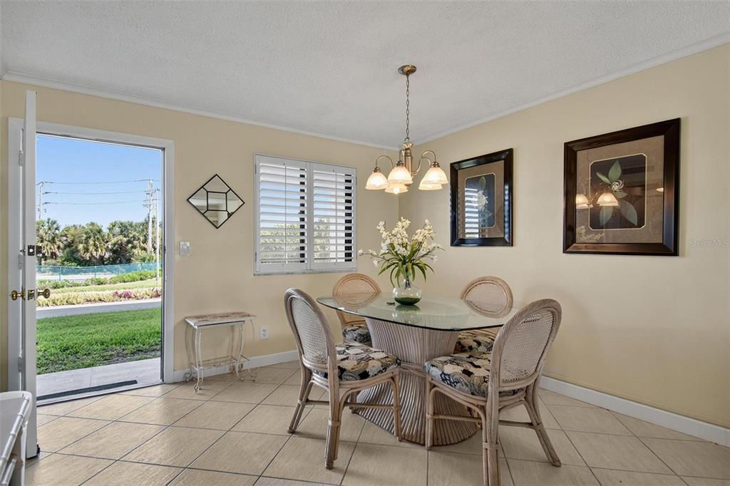 A dining area features a glass-topped table, wicker chairs, tile flooring, and a sliding door — 3500 S OCEAN SHORE BOULEVARD UNIT 109, FLAGLER BEACH, FL