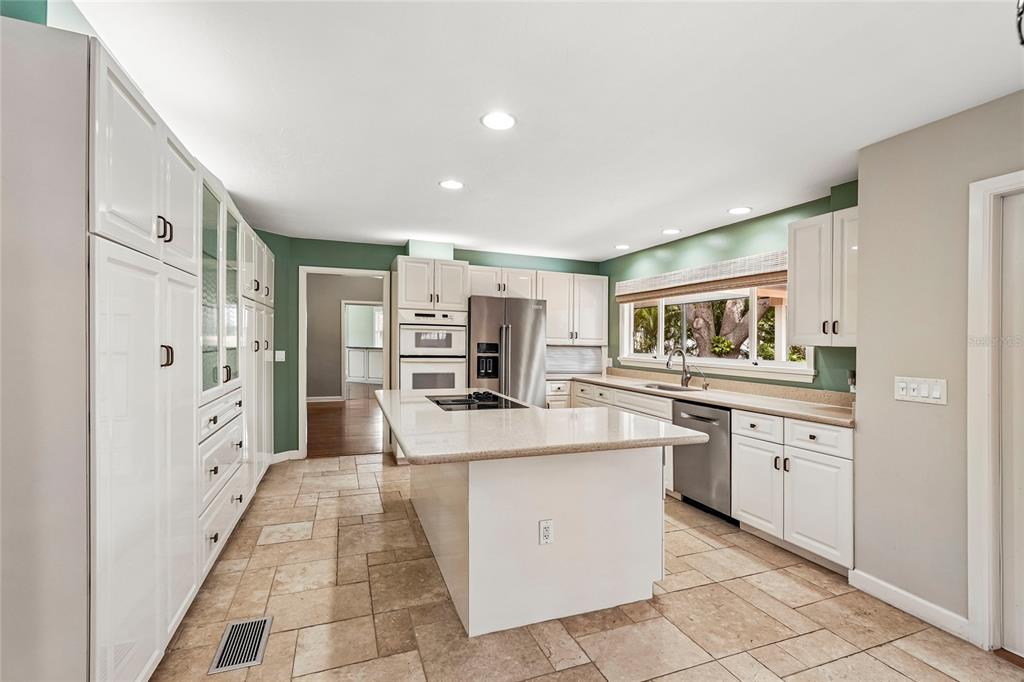 A kitchen features white cabinetry, a central island with a stone countertop, and tile flooring — 1675 LANDINGS LANE, SARASOTA, FL