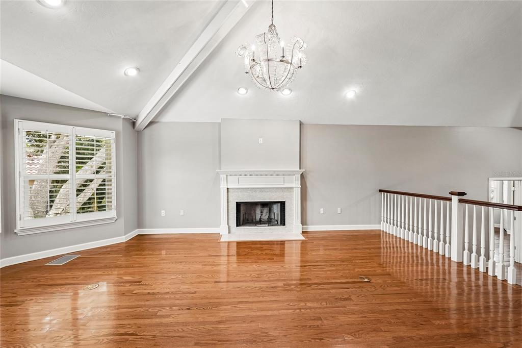 A spacious living room features hardwood floors, a fireplace, a chandelier, and a vaulted ceiling — 1675 LANDINGS LANE, SARASOTA, FL