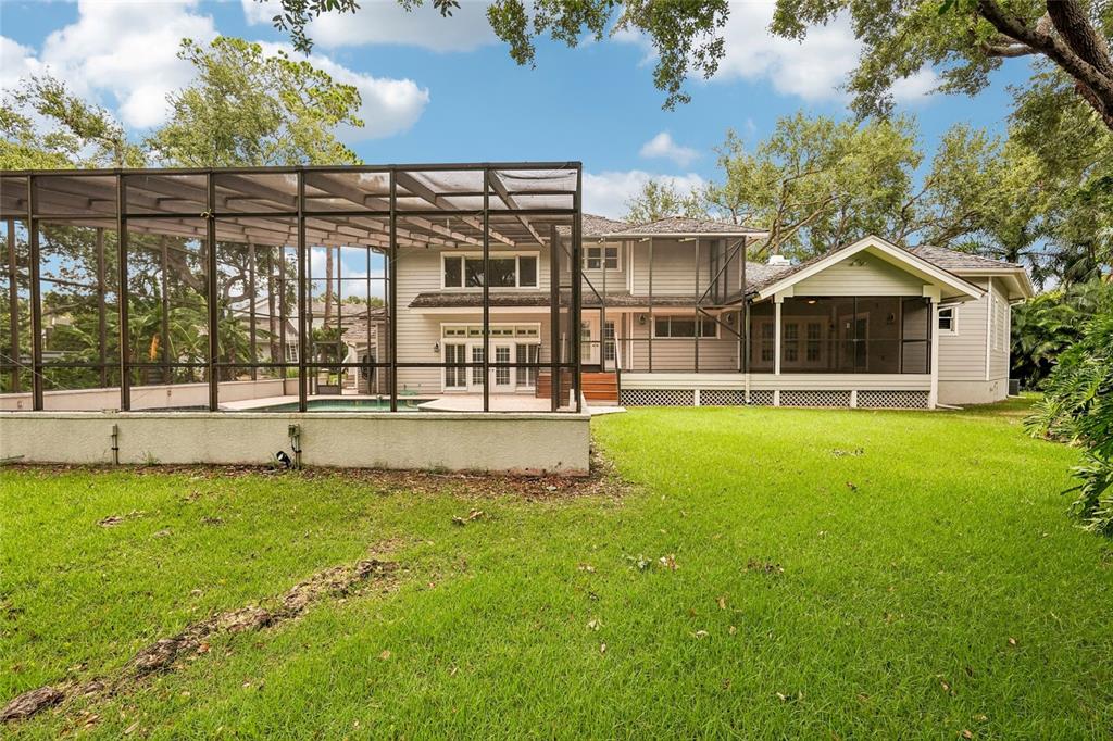 The rear exterior of a two-story house features a screened-in pool and a covered patio — 1675 LANDINGS LANE, SARASOTA, FL