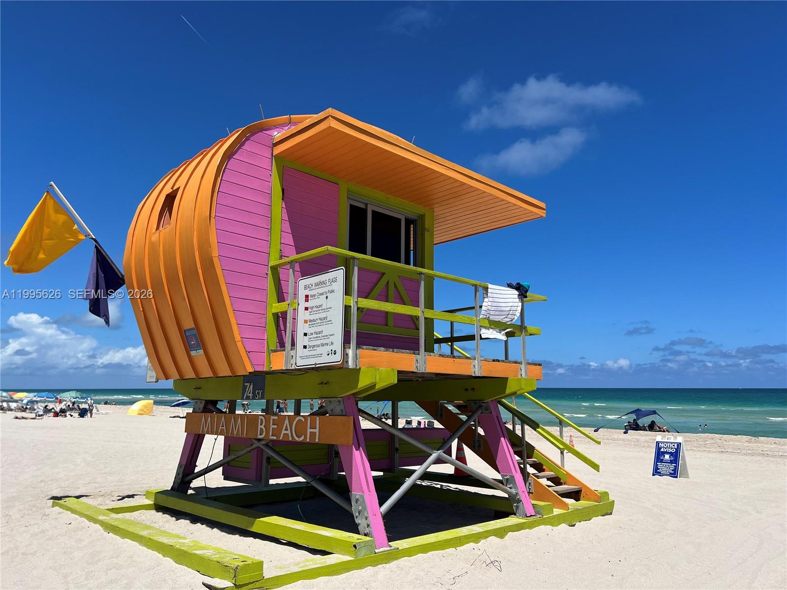 A colorful, elevated lifeguard tower stands on a sandy beach under a clear blue sky — 330 74th St # 5, Miami Beach FL 33141, MIAMI BEACH, FL
