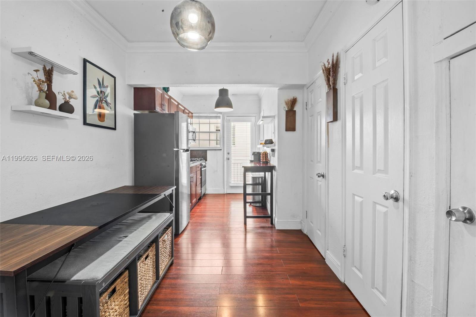 A kitchen features stainless steel appliances, wood-toned cabinetry, and a dining bench with storage baskets — 330 74th St # 5, Miami Beach FL 33141, MIAMI BEACH, FL