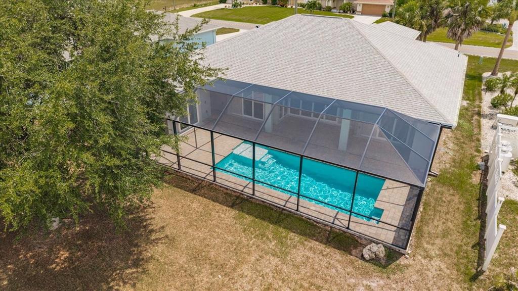 An aerial view of a house with a screened-in swimming pool and a large tree — 777 BOUNDARY BOULEVARD, ROTONDA WEST, FL