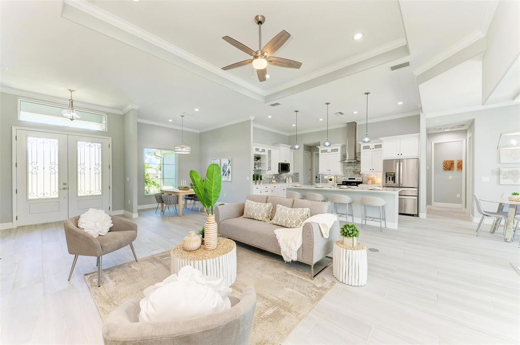 An open-concept living room and kitchen featuring light tile flooring and a tray ceiling — 777 BOUNDARY BOULEVARD, ROTONDA WEST, FL