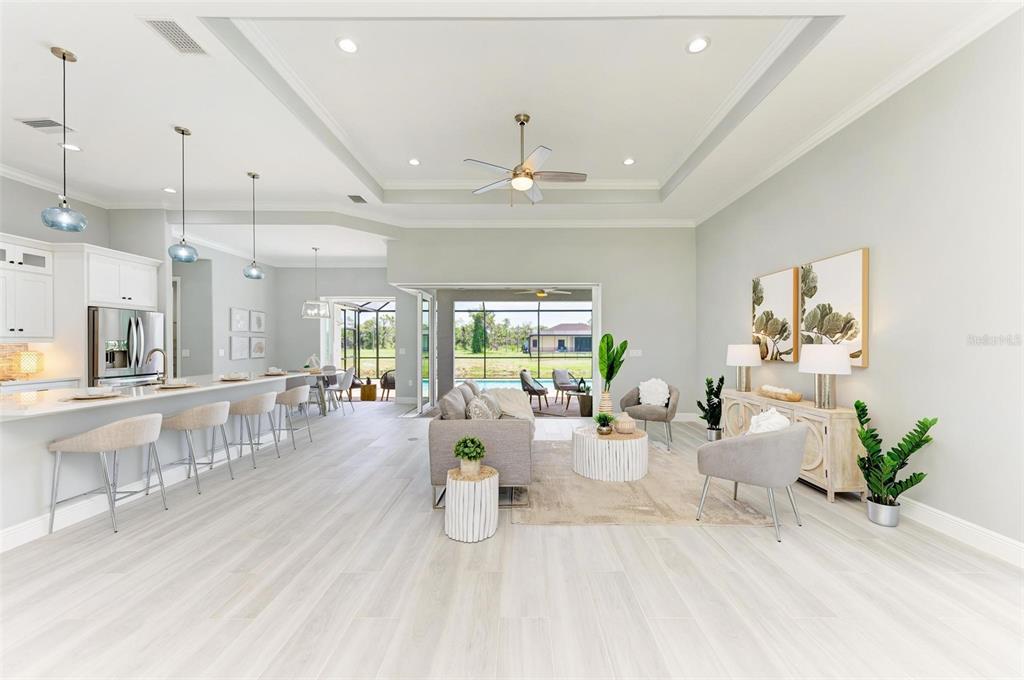An open-concept living room and kitchen feature light wood flooring and a tray ceiling — 777 BOUNDARY BOULEVARD, ROTONDA WEST, FL