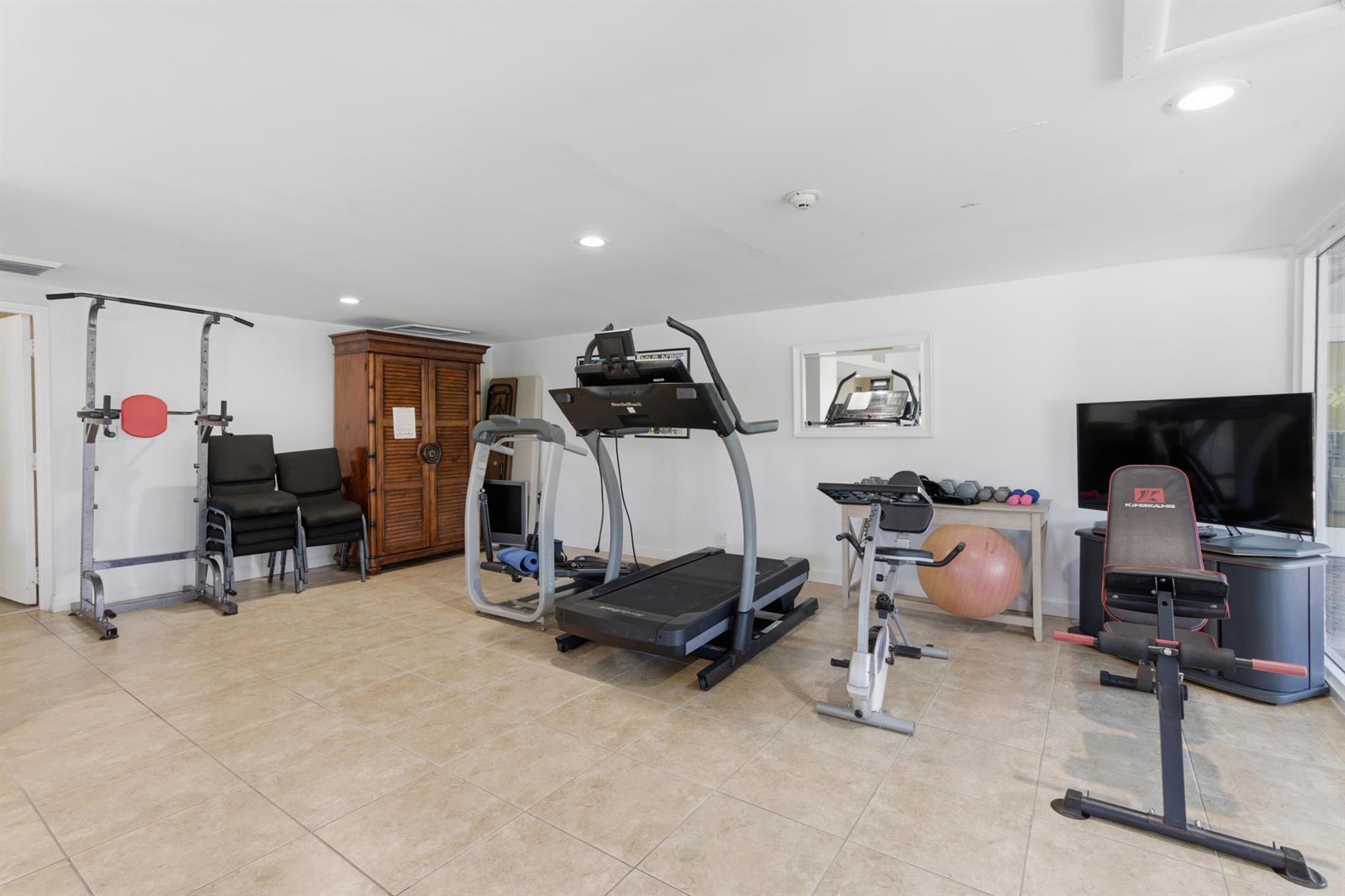 A home gym features a treadmill, exercise bike, weight bench, and tile flooring — 3581 S Ocean Boulevard Apt 4e, South Palm Beach FL 33480, SOUTH PALM BEACH, FL