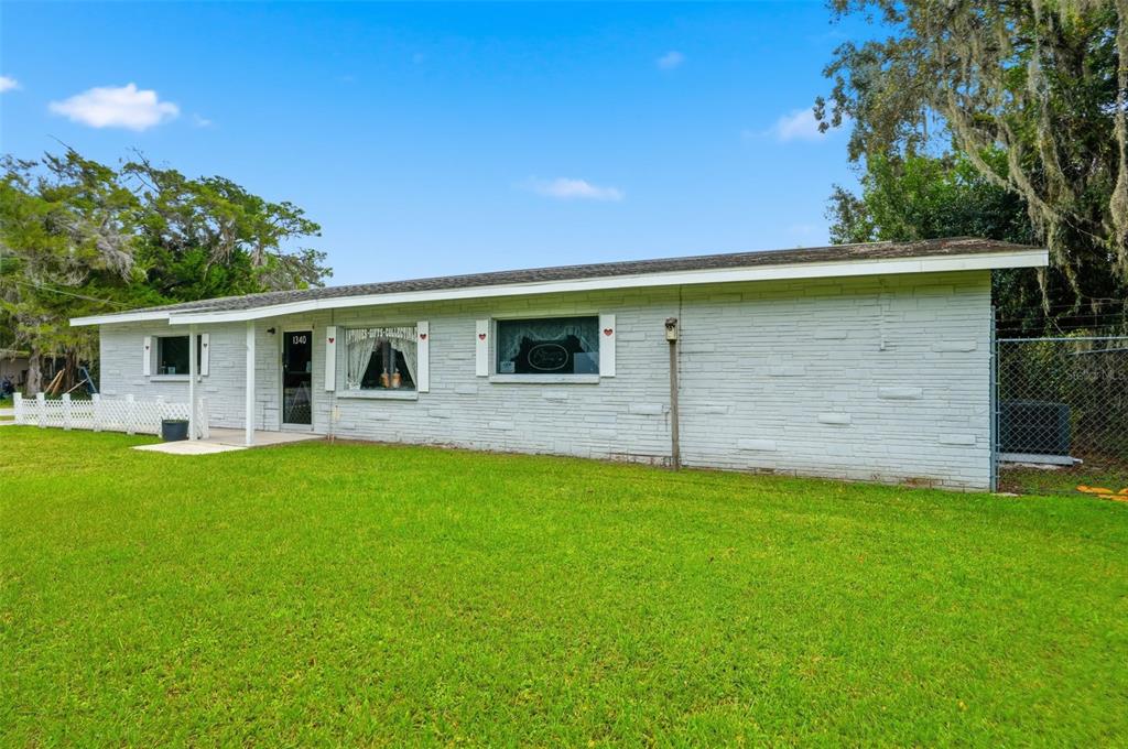A single-story house with a white painted brick exterior and a green lawn — 1340 HOWELL AVENUE, BROOKSVILLE, FL