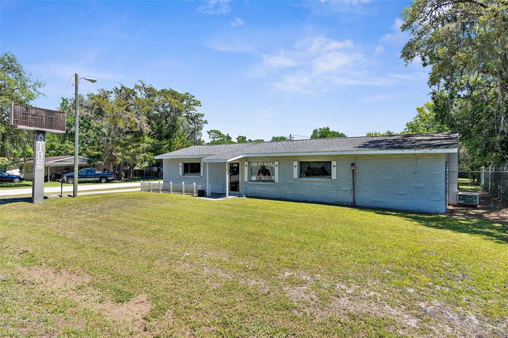 A single-story building with light-colored siding and a sign reading Antiques stands on a lawn — 1340 HOWELL AVENUE, BROOKSVILLE, FL
