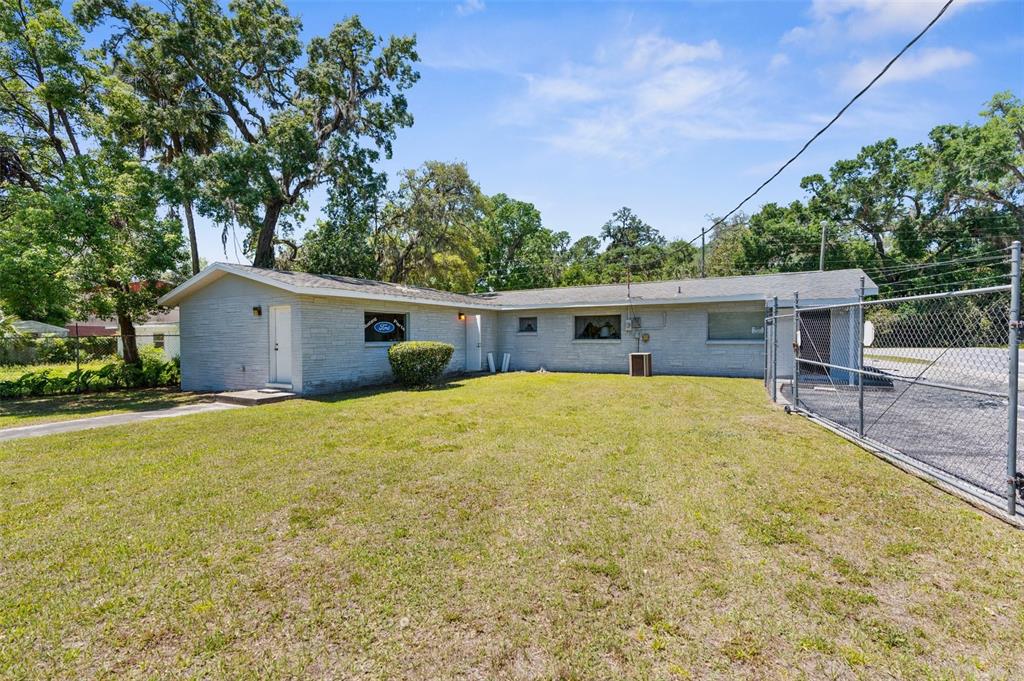 A single-story light gray brick building sits on a grassy lot next to a chain-link fence — 1340 HOWELL AVENUE, BROOKSVILLE, FL