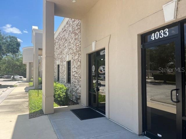The exterior of a commercial building features a stone facade, concrete walkway, and glass doors — 4031 W STATE ROAD 46 UNIT C, SANFORD, FL